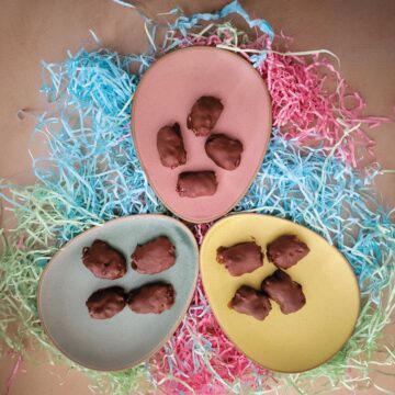 Coconut eggs on pastel colored plates with different color Easter grass around them for decoration.
