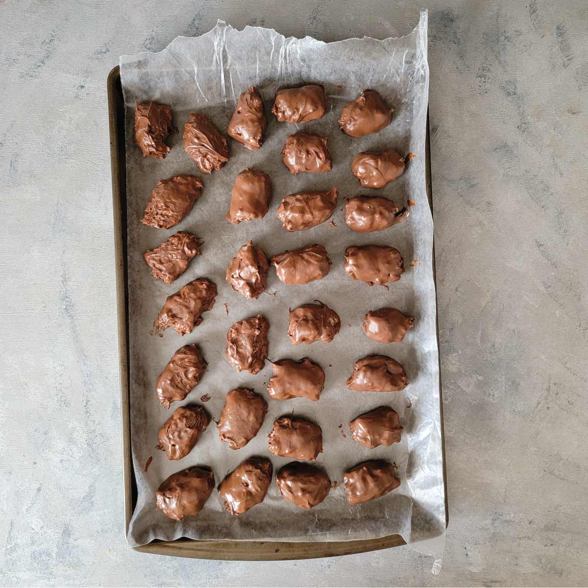 Eggs on wax paper on a baking sheet after coating in chocolate.