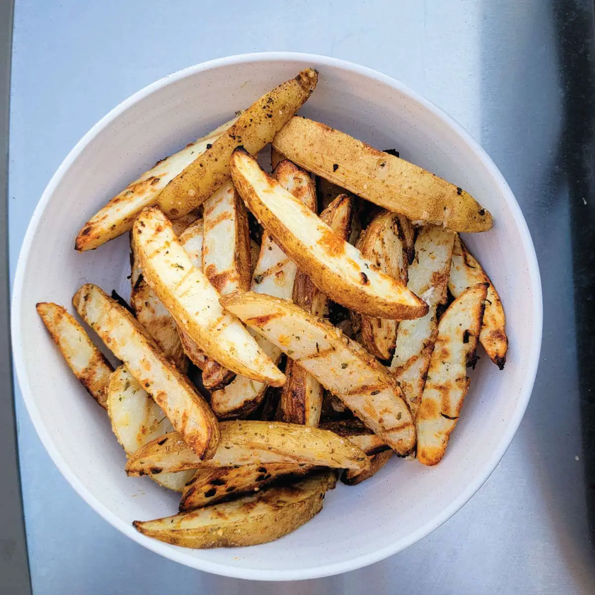 Potato wedges in a bowl after being grilled ready to serve.