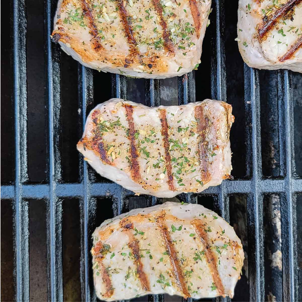 Pork chops on the grill after being flipped over.