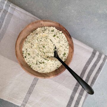 Ranch seasoning mix in a small wood bowl with a spoon scooping some out.