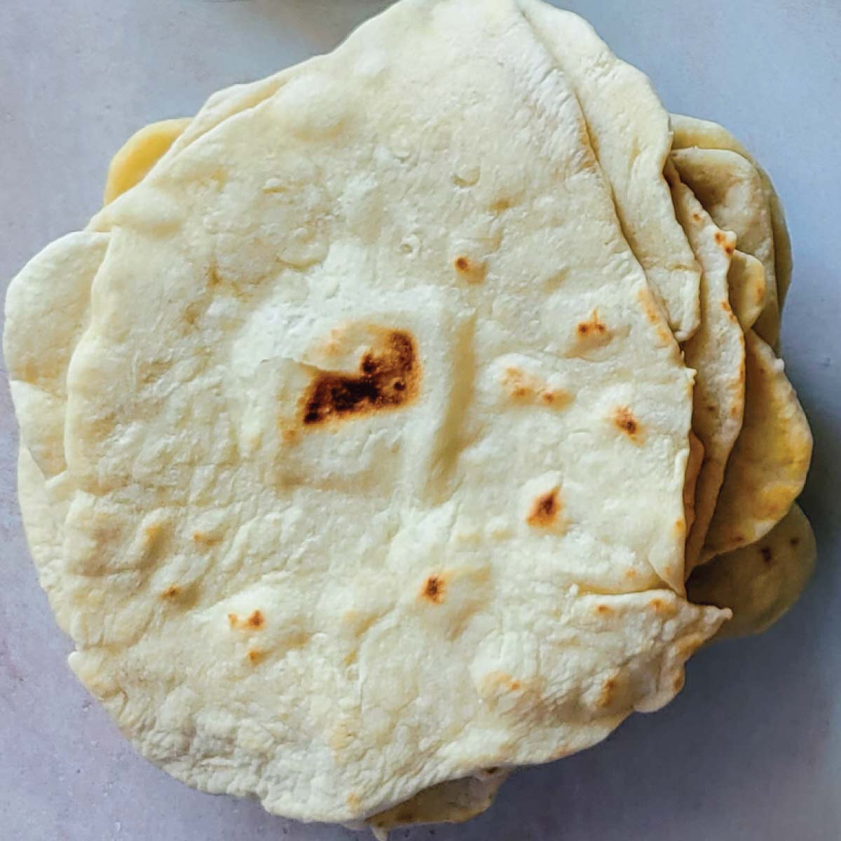 Homemade flour tortillas stacked up in a pile ready to use.