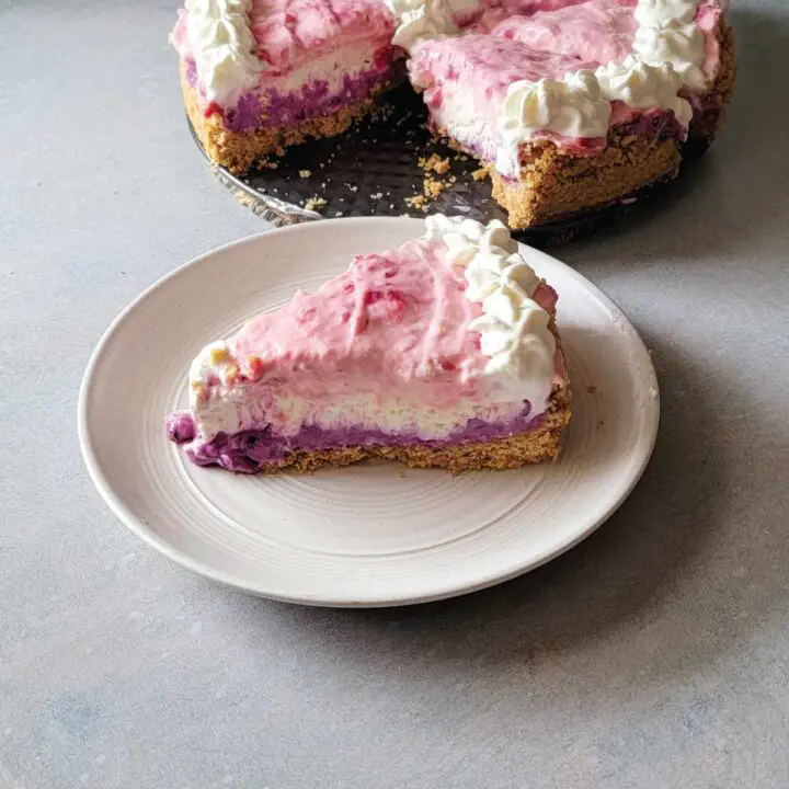 No bake strawberry blueberry cheesecake cut with a slice on a dessert plate ready to eat.