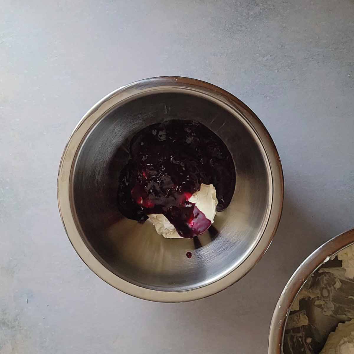 Blueberry sauce poured over 1 cup of filling ready to mix together in a mixing bowl.