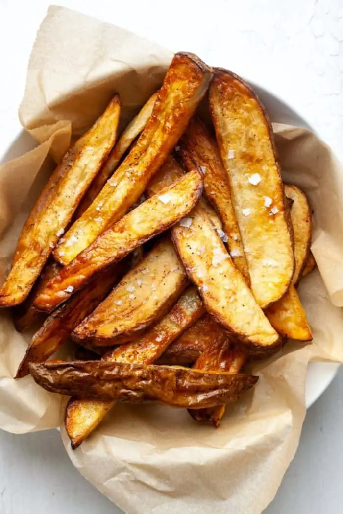 Potato wedges in a dish with salt on them ready to serve.