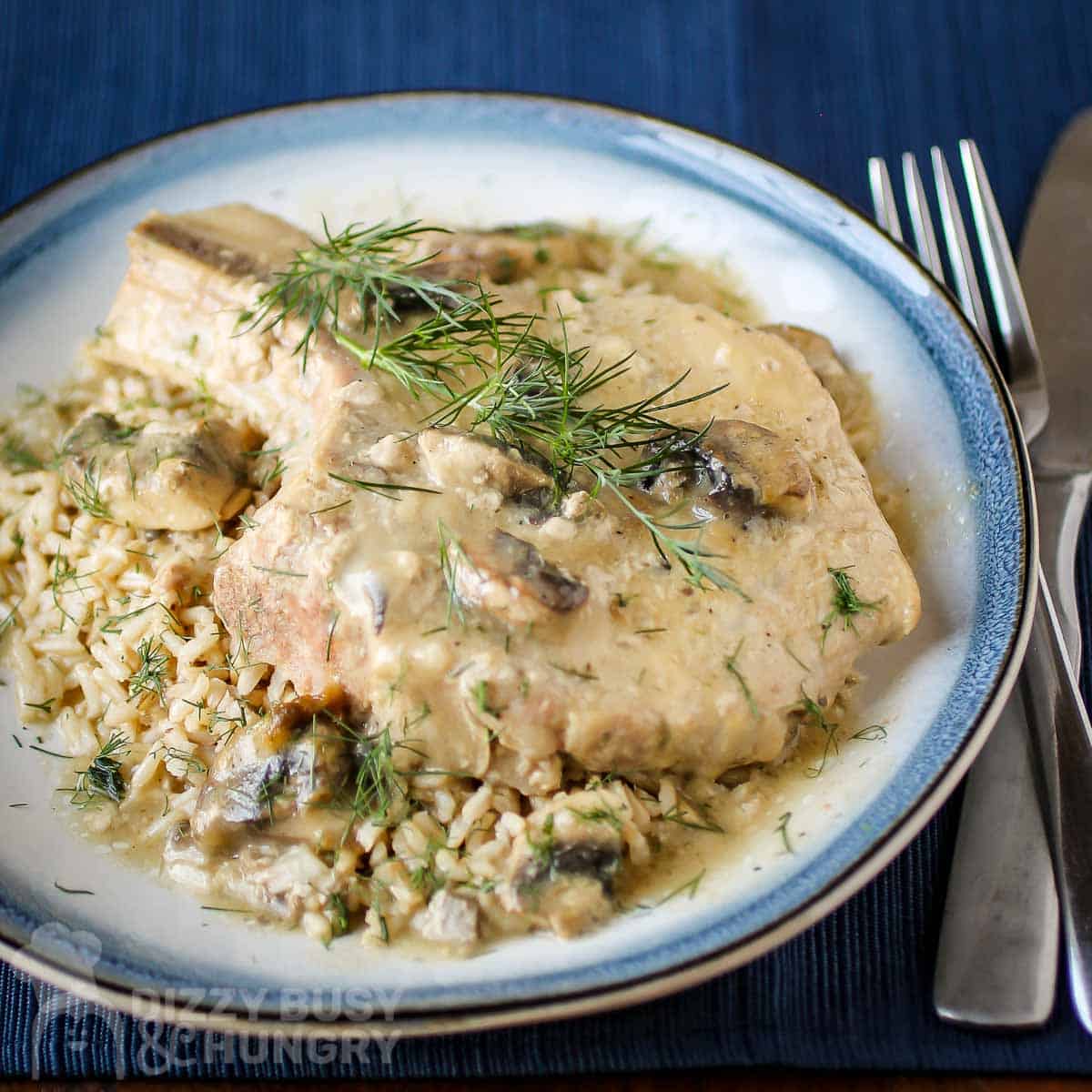 Creamy pork chop over top rice on a plate ready to serve.