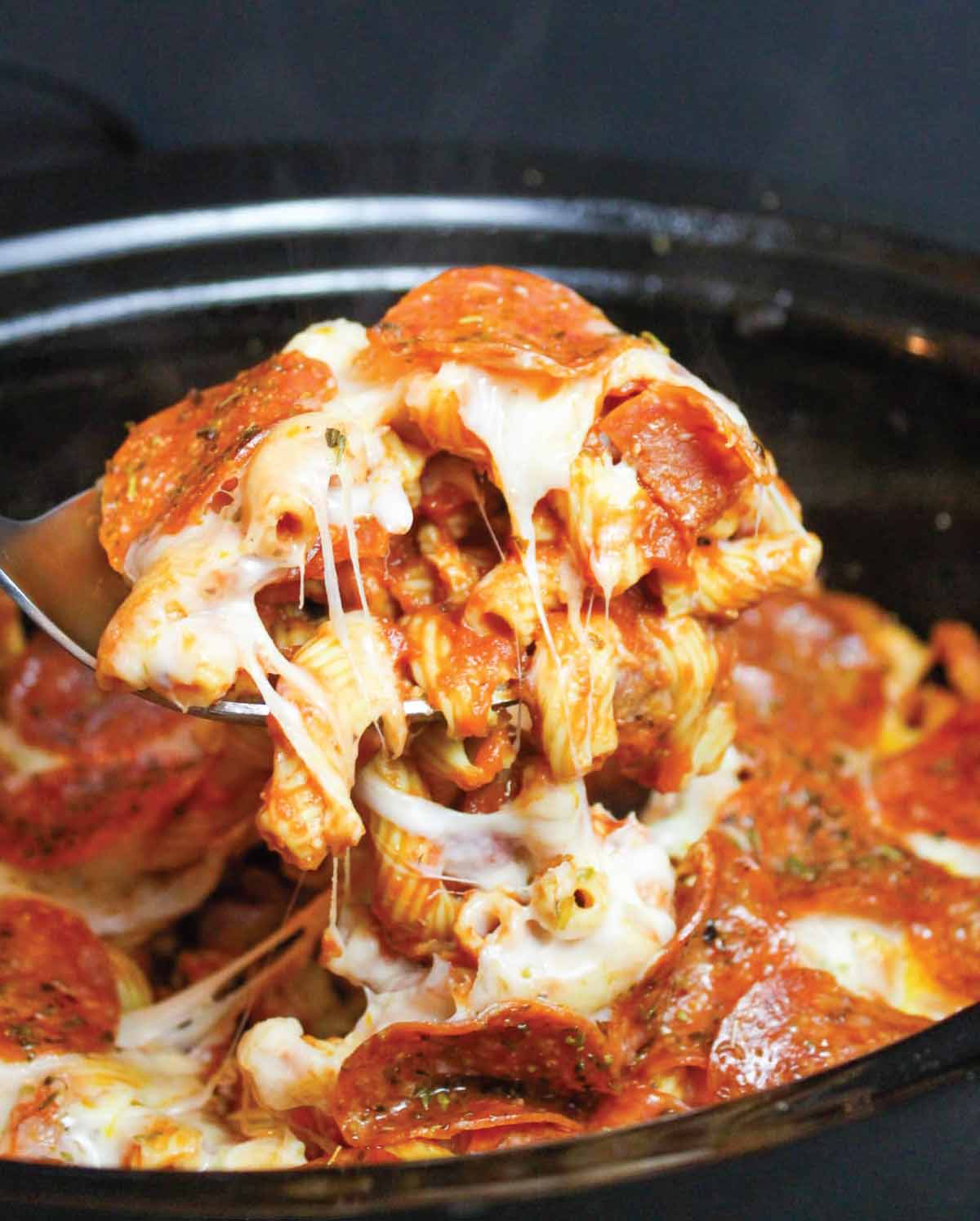 pepperoni pizza pasta being spooned out of the crock pot to serve.