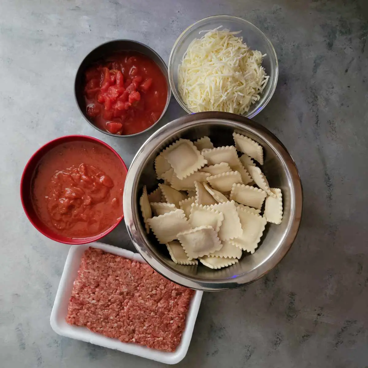Ingredients prepped - ground sausage, frozen raviolis, marinara sauce, cheese and diced tomatoes.