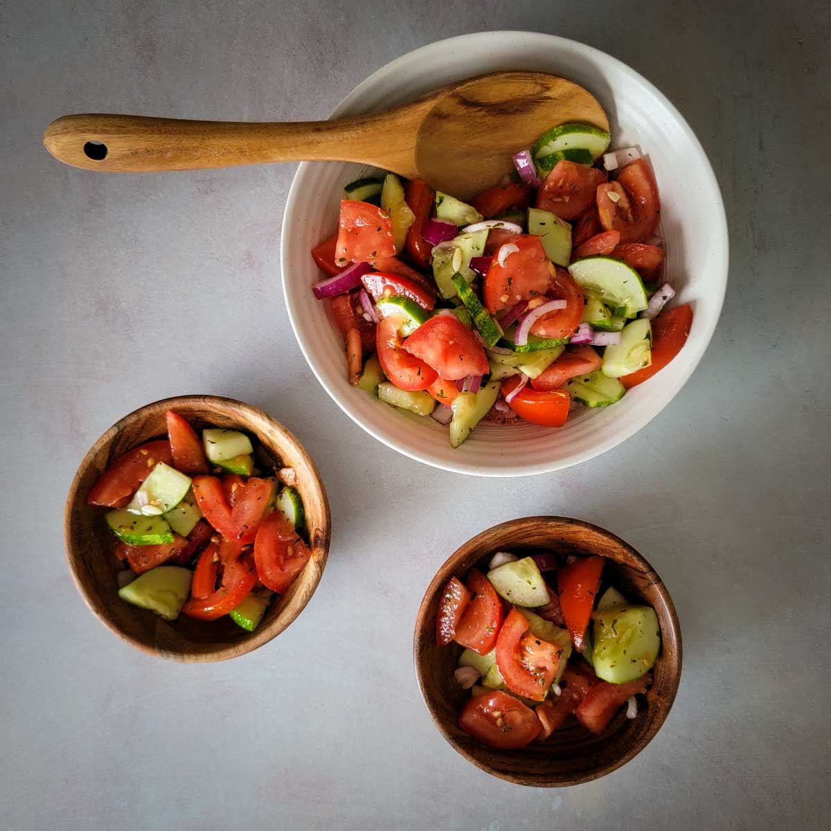 Tomato cucumber salad dished out into serving bowls ready to eat.