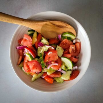 Cucumber tomato salad mixed together in a bowl ready to serve.