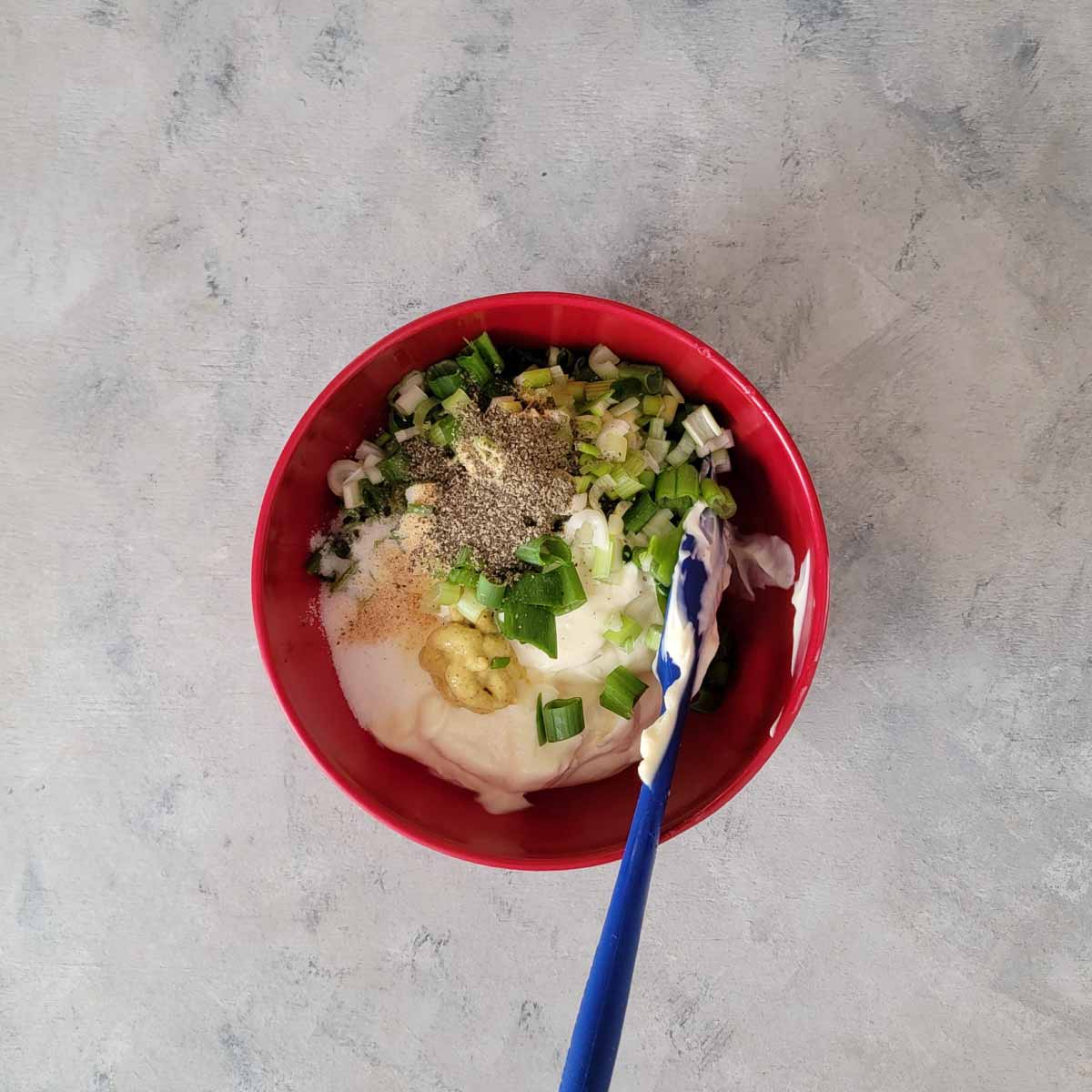 Mayo, vinegar, mustard, salt, garlic, chopped scallions, celery seed, pepper and sugar in a small prep bowl ready to be mixed.