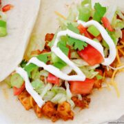 Soft potato taco topped with shredded lettuce, chopped tomatoes, cheese and sour cream.