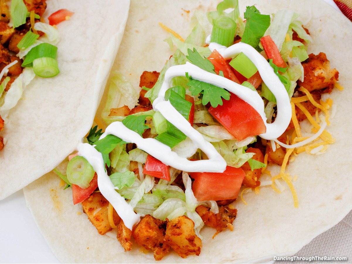 Soft potato taco topped with shredded lettuce, chopped tomatoes, cheese and sour cream.