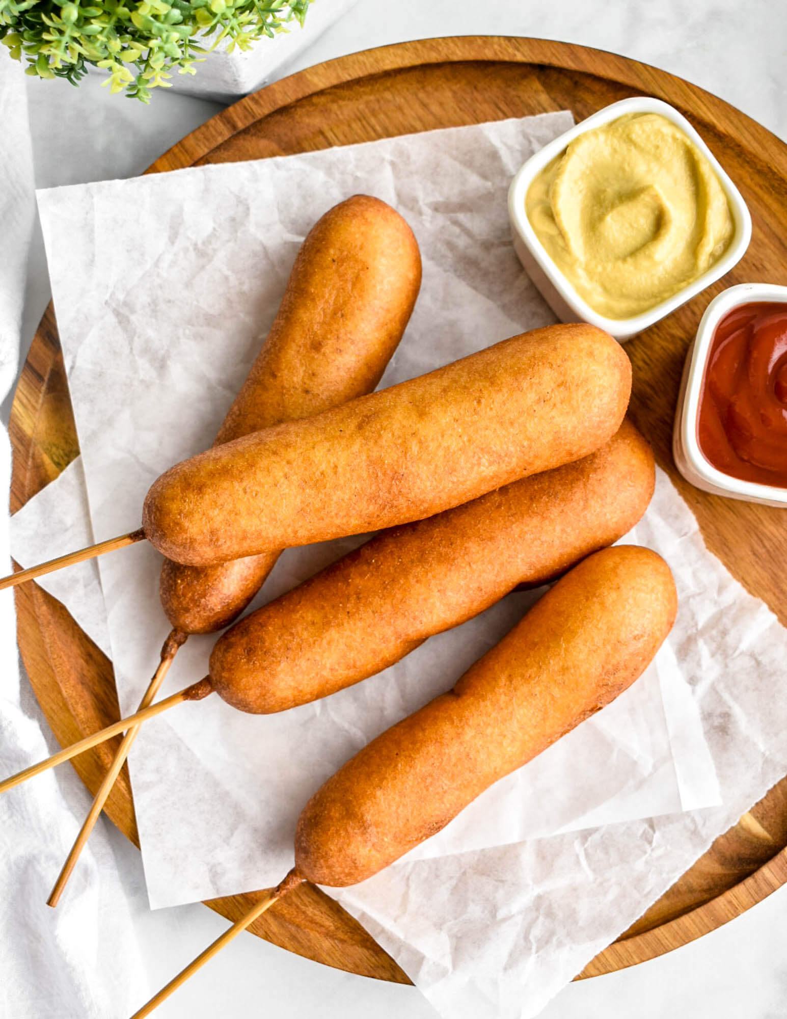 Corn dogs on a serving tray with mustard and ketchup in small prep bowls for dipping.