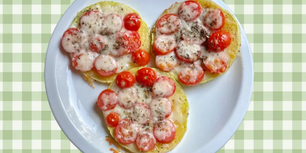 3 squash mini pizzas with melted cheese on top on a serving plate ready to serve.