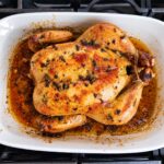 Oven roasted chicken just out of the oven still in the baking dish with a golden crispy skin.