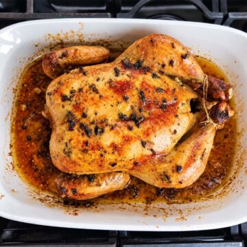 Oven roasted chicken just out of the oven still in the baking dish with a golden crispy skin.