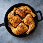 Leg quarters cooked to perfection with golden brown skin in a cast iron pan ready to serve.