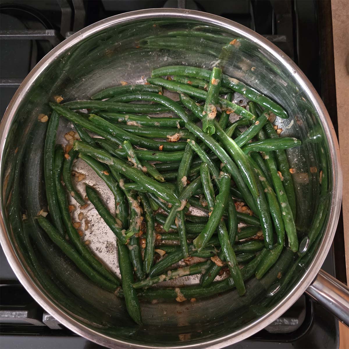 Green beans in a skillet covered in garlic butter right before adding parmesan cheese.